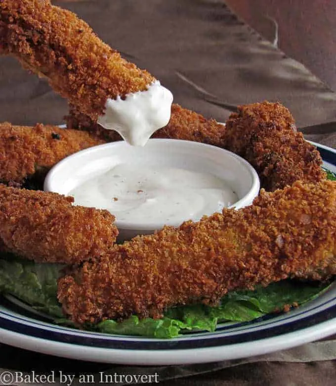 Fried Pickle Spear being dipped in a ramekin of ranch dressing.