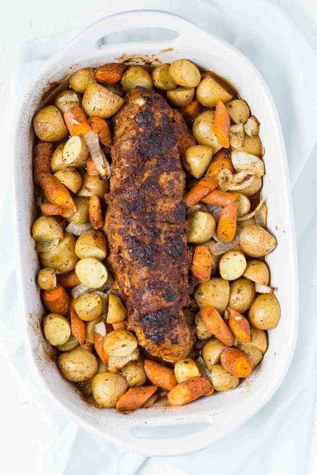 Overhead view of Tomato Roasted Pork Loin with potatoes and carrots in a white casserole.