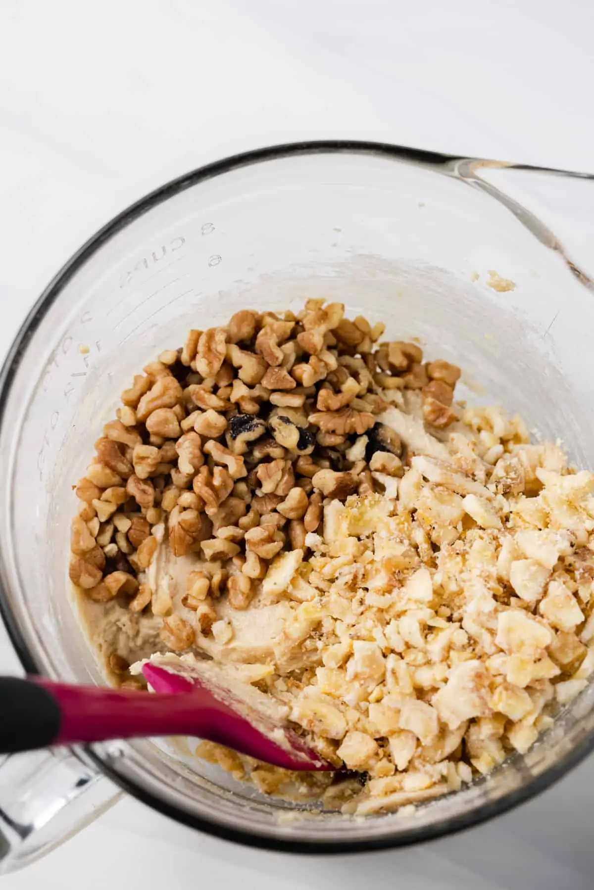 Walnuts and crushed banana chips being stirred into cookie batter