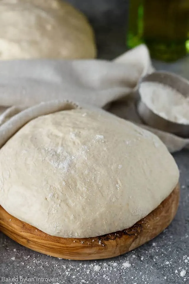 close up of pizza dough on a wooden board