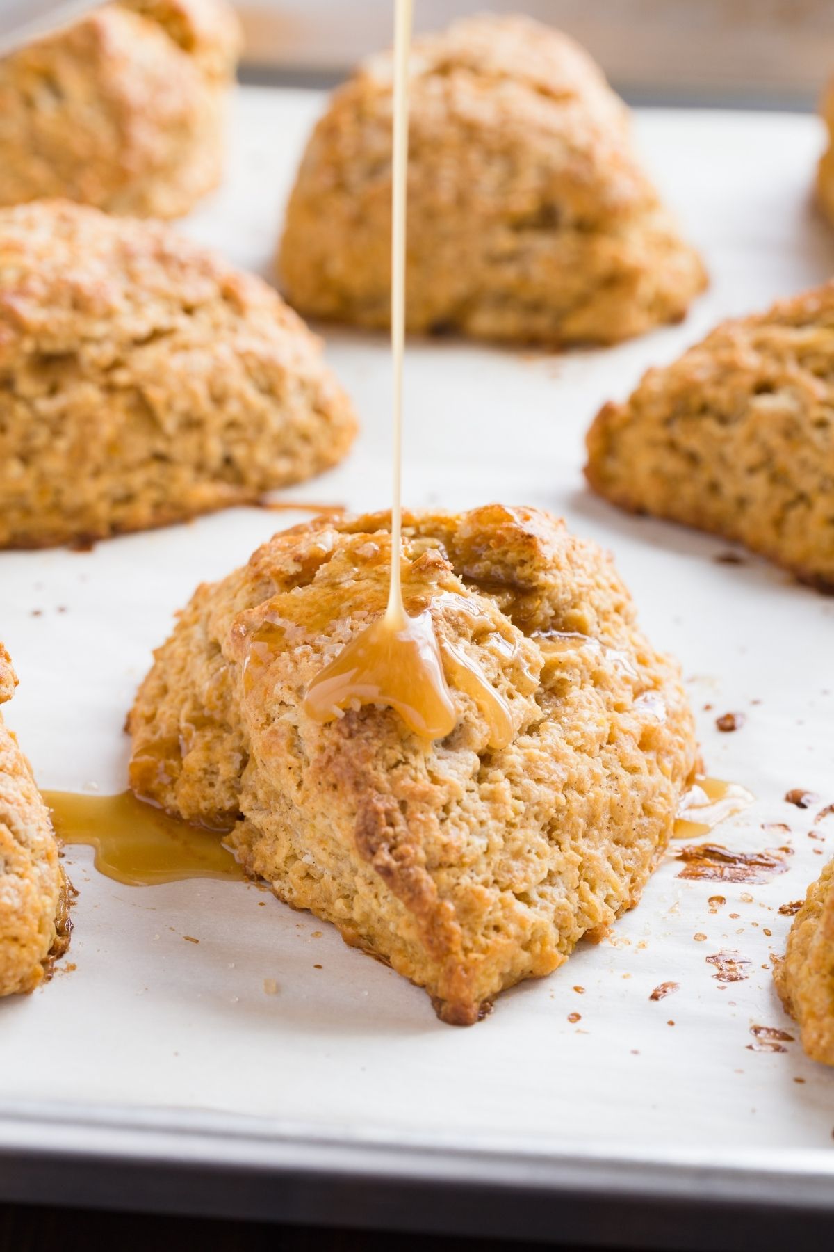 Honey citrus glaze being drizzled over baked sweet potato scones.