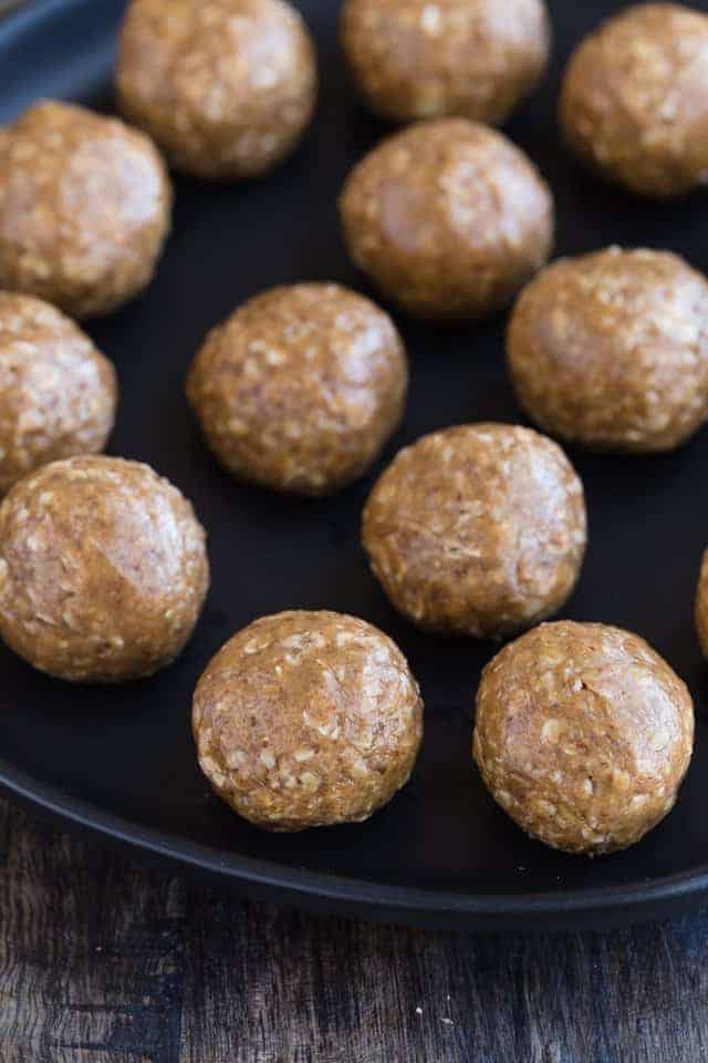 Close up view of almond butter oat balls on a black plate.