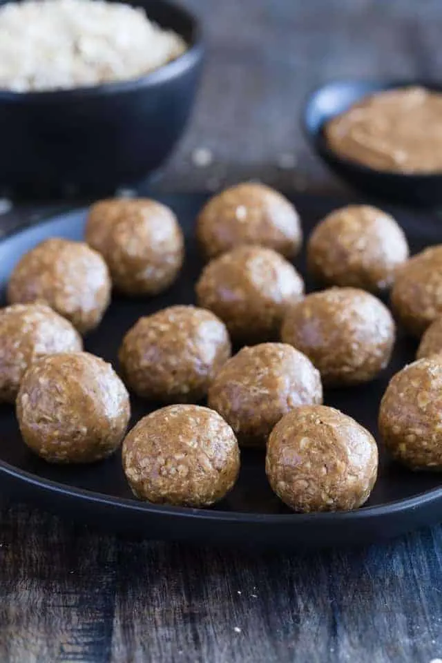 Front view of almond butter energy bites on a black plate.