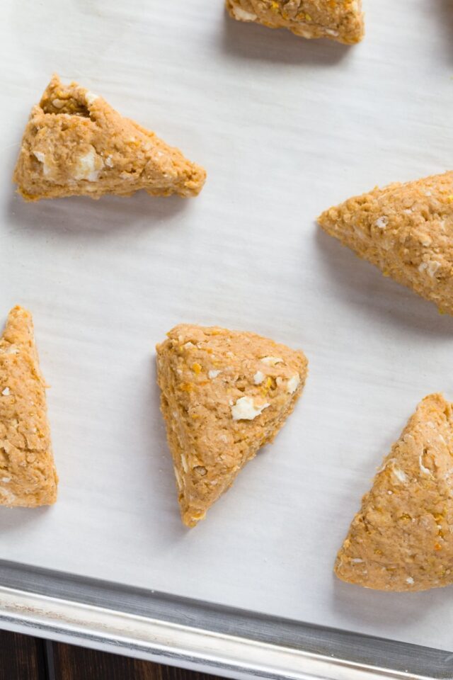 Unbaked sweet potato scone triangles on a baking sheet lined with parchment paper.