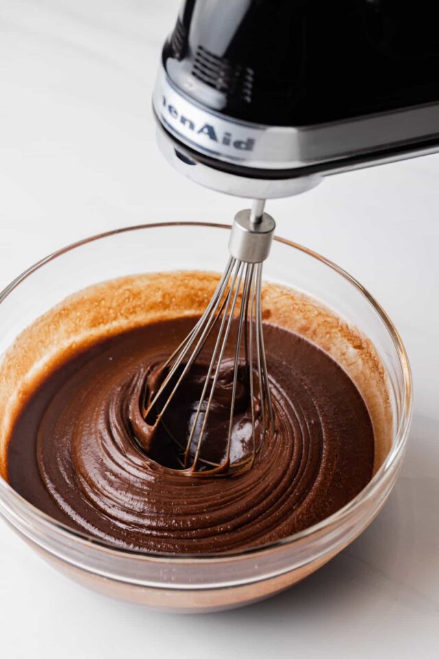 Melted chocolate in a glass bowl with a hand mixer