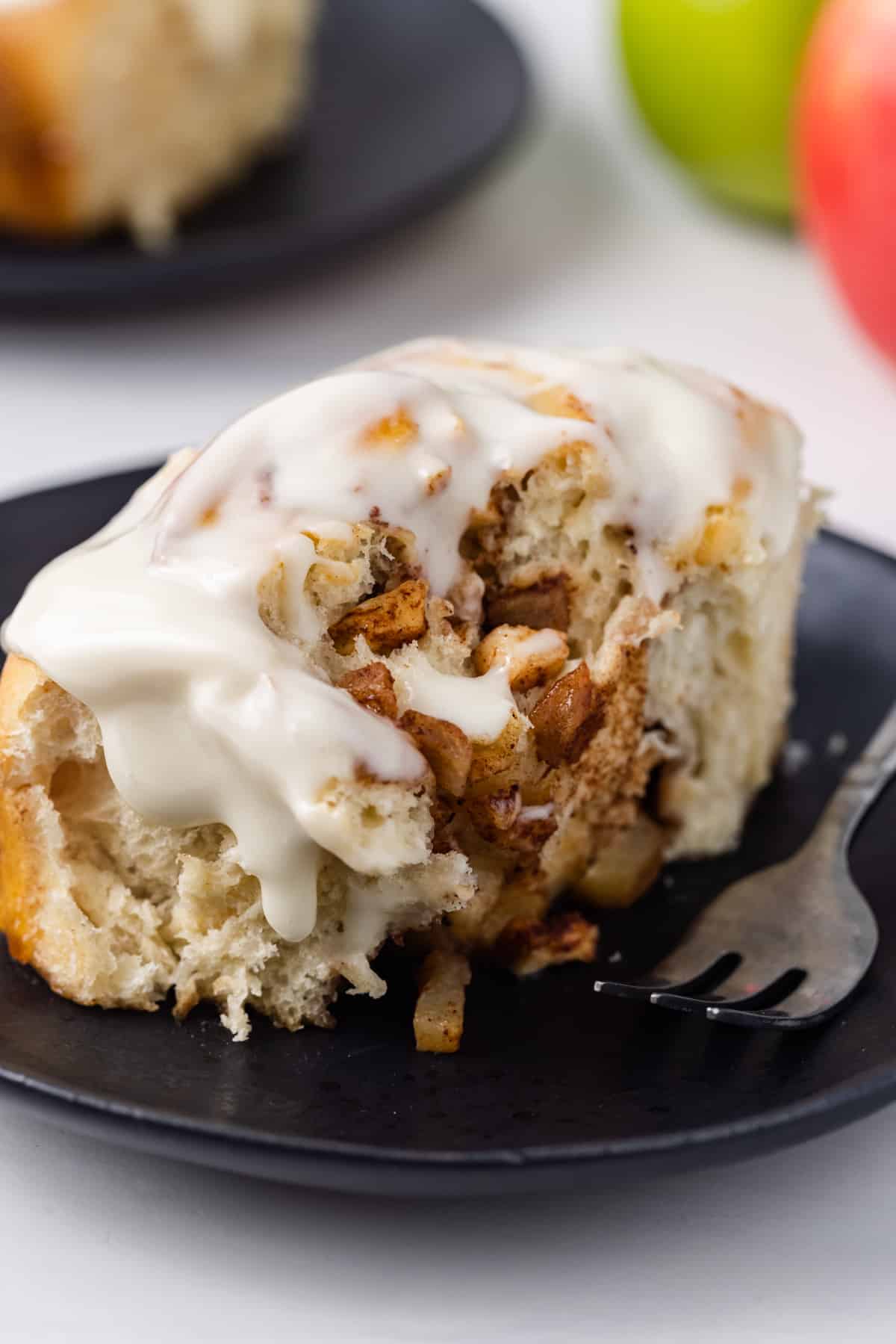 Freshly baked glazed apple cinnamon rolls on a plate with a fork