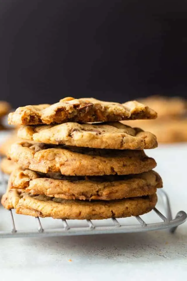 four and a half butterscotch toffee cookies stacked on a wire rack