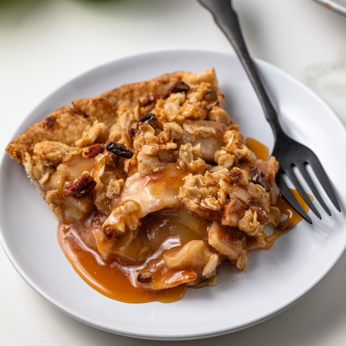 Slice of caramel apple pecan streusel pie on a plate.