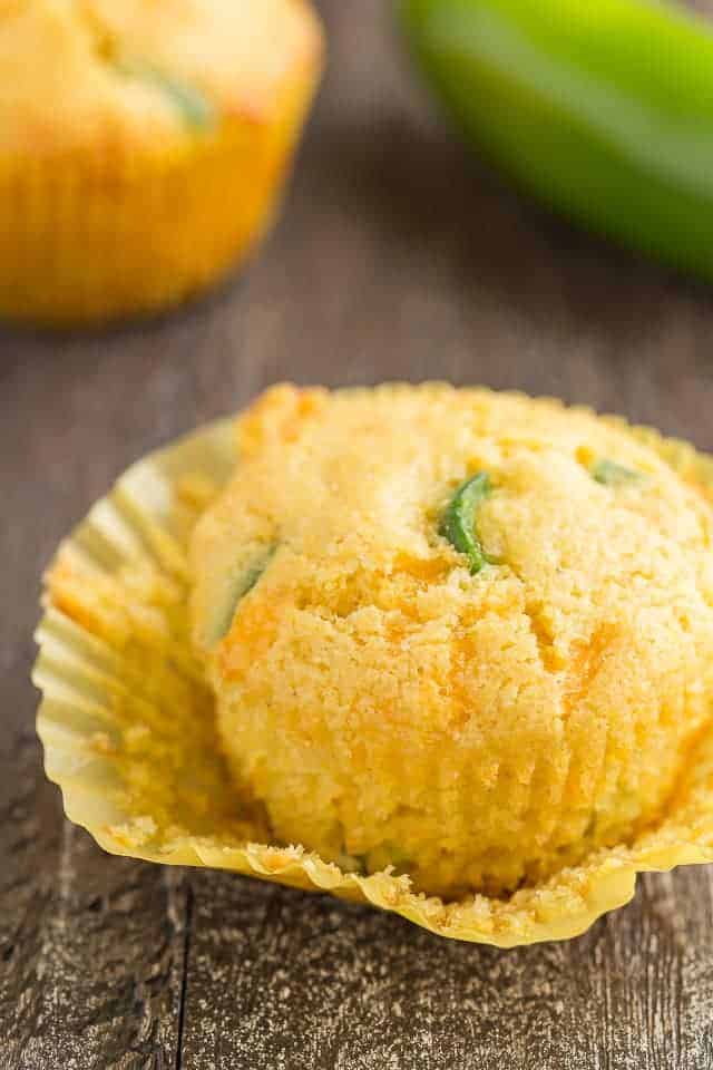 Side view of a cheddar jalapeno cornbread muffin with the paper liner pulled away.