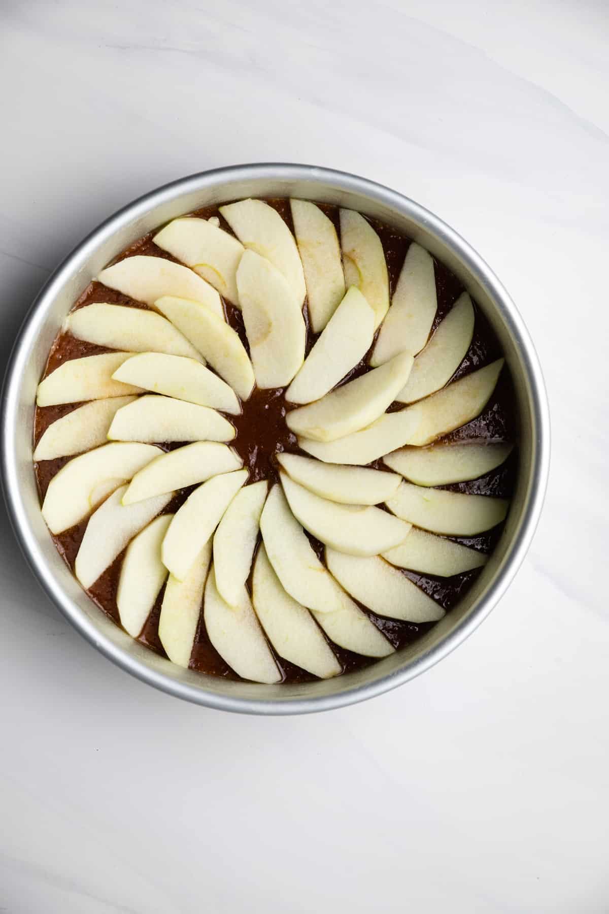 Apple slices in the bottom of a round cake pan