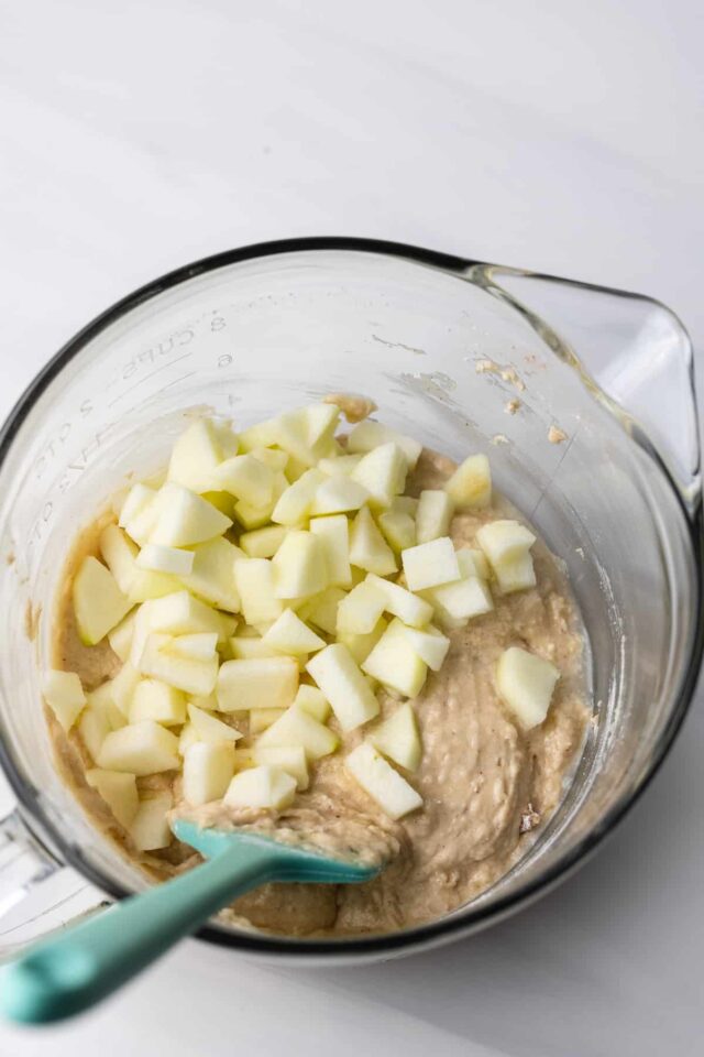 Apple pieces being stirred into cake batter
