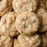 closeup overhead view of white chocolate chip cookies with toasted coconut on white parchment paper