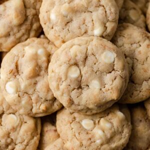 closeup overhead view of white chocolate chip cookies with toasted coconut on white parchment paper