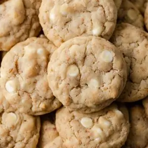 closeup overhead view of white chocolate chip cookies with toasted coconut on white parchment paper