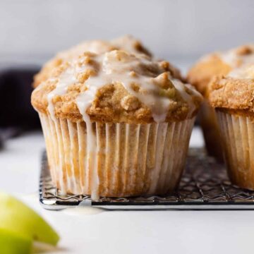 Two apple streusel muffins topped with glaze