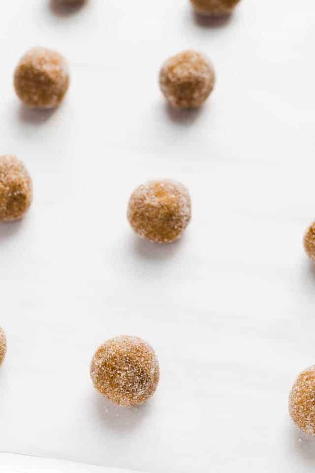 Gingersnap cookie dough balls rolled in sugar lined up on a baking sheet.