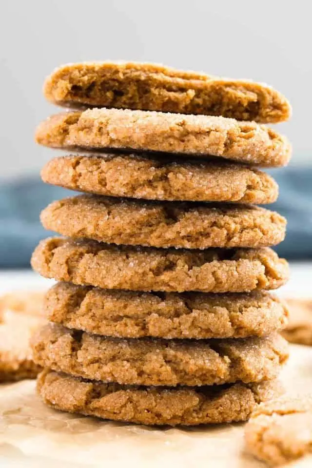 A stack of chewy gingersnap cookies on a white counter with a blue cloth napkin in the background.