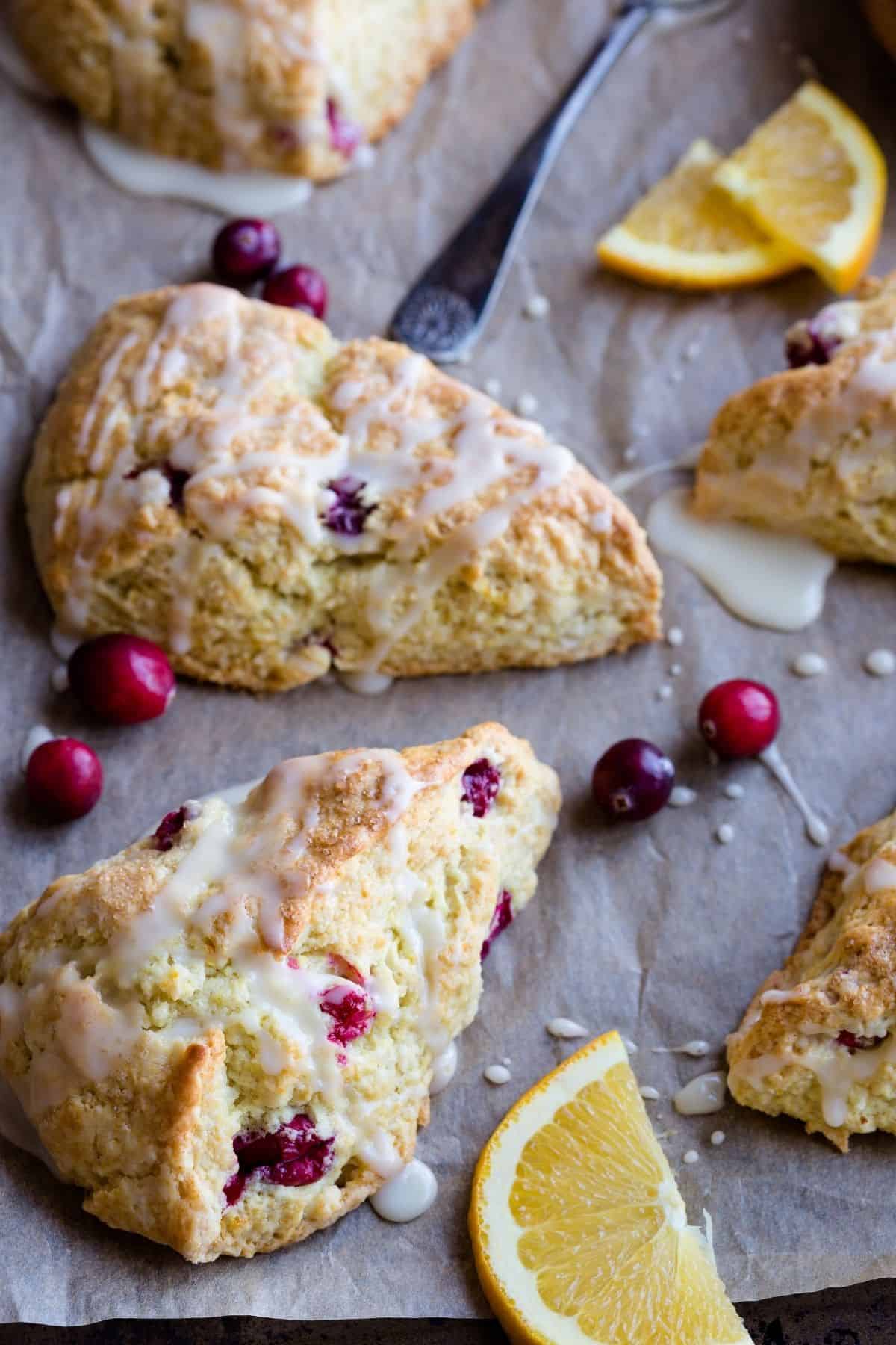 Cranberry orange scones on a baking sheet with cranberries and orange slices