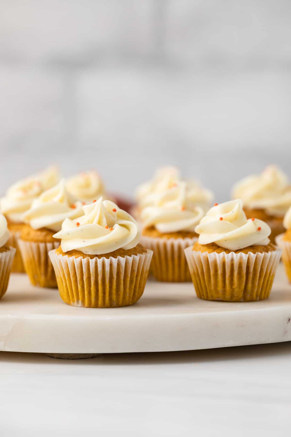 Mini pumpkin cupcakes with cream cheese frosting on a serving platter
