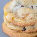 three chocolate chunk apricot cookies stacked on a gray background
