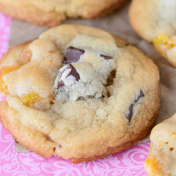angled view of chocolate chunk apricot cookies on a pink fabric