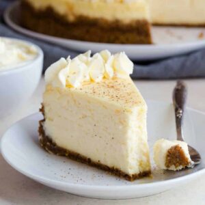 Eggnog cheesecake on white plate with a fork taking a bite out.