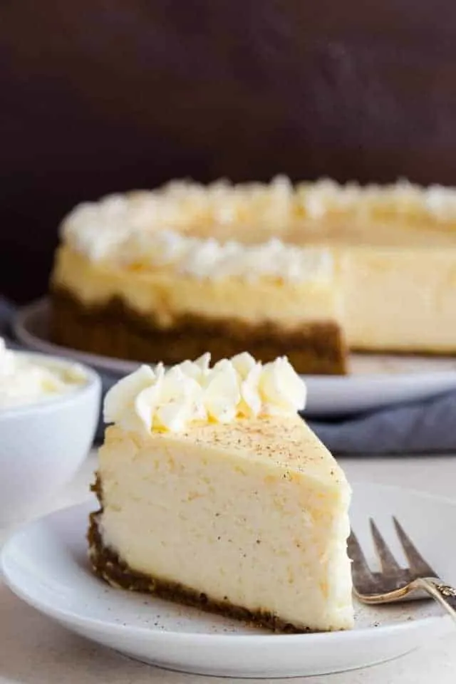 Eggnog Cheesecake Eggnog Cheesecake on a white plate with a fork next to it.