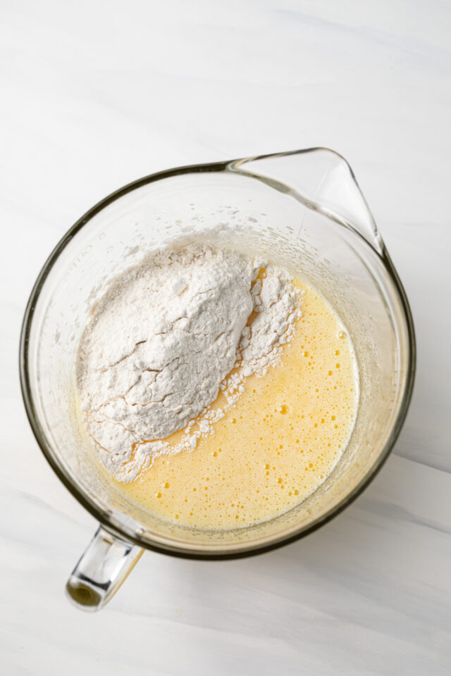 Flour added to a bowl with creamed butter and sugar.