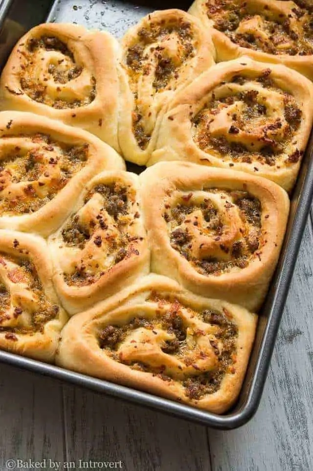 angled view of sausage and cheese breakfast rolls in a baking pan