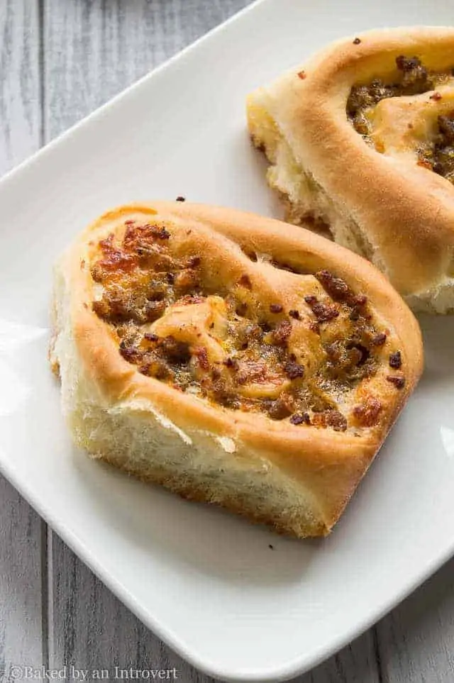 angled view of sausage and cheese breakfast rolls on a white plate