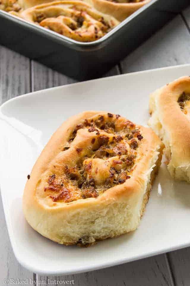 side view of sausage and cheese breakfast rolls on a white plate