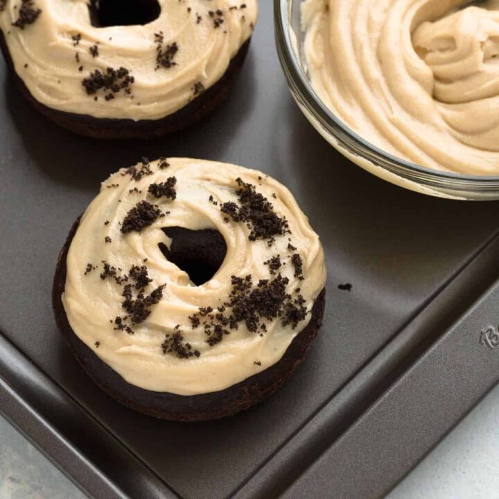 Angled view of Baked Chocolate Donuts with Peanut Butter Frosting on a baking sheet.