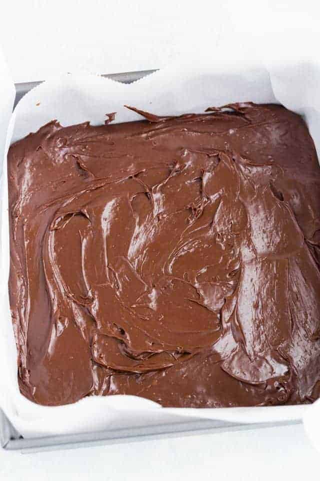 Mexican hot chocolate fudge pressed into a square baking pan lined with parchment paper.