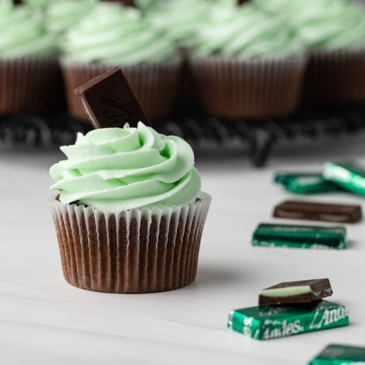 Andes mint cupcakes on wire rack with one in front.