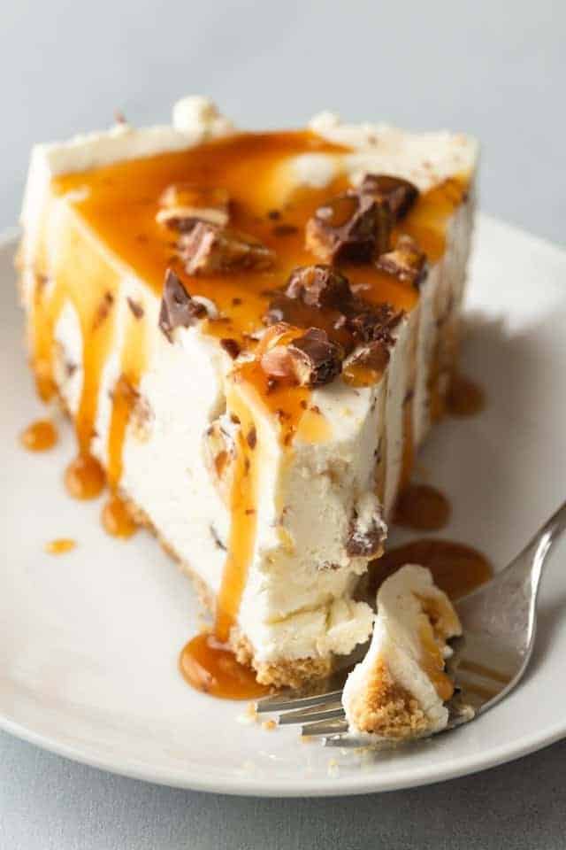 slice of no bake snickers cheesecake with a fork taking out a bite