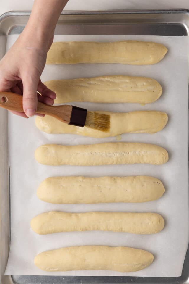 Brushing butter over proofed breadsticks.