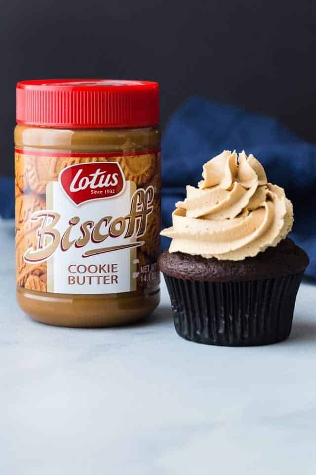 A jar Biscoff Cookie Butter next to a chocolate cupcake topped with Biscoff cookie butter frosting.