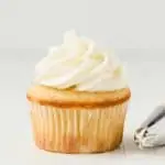 Coconut buttercream frosting swirled on top of a vanilla cupcake.