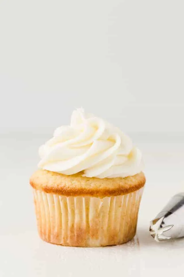 Coconut buttercream frosting swirled on top of a vanilla cupcake.