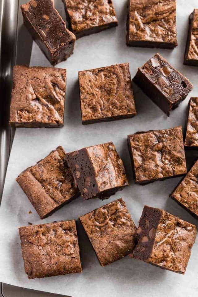 Double chocolate brownies scattered on a baking sheet lined with parchment paper.