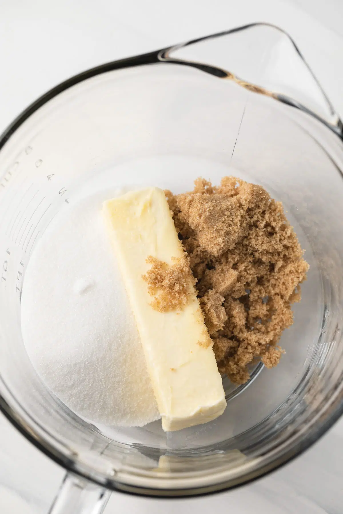 Butter, sugar, and brown sugar in a glass bowl.