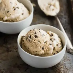 Angled view of two bowls of coffee crunch ice cream on an old baking sheet.