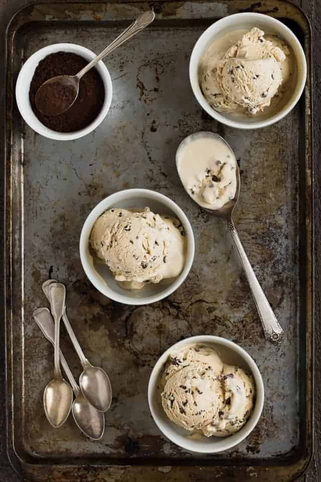 Three bowls of coffee crunch ice cream on an old baking sheet.