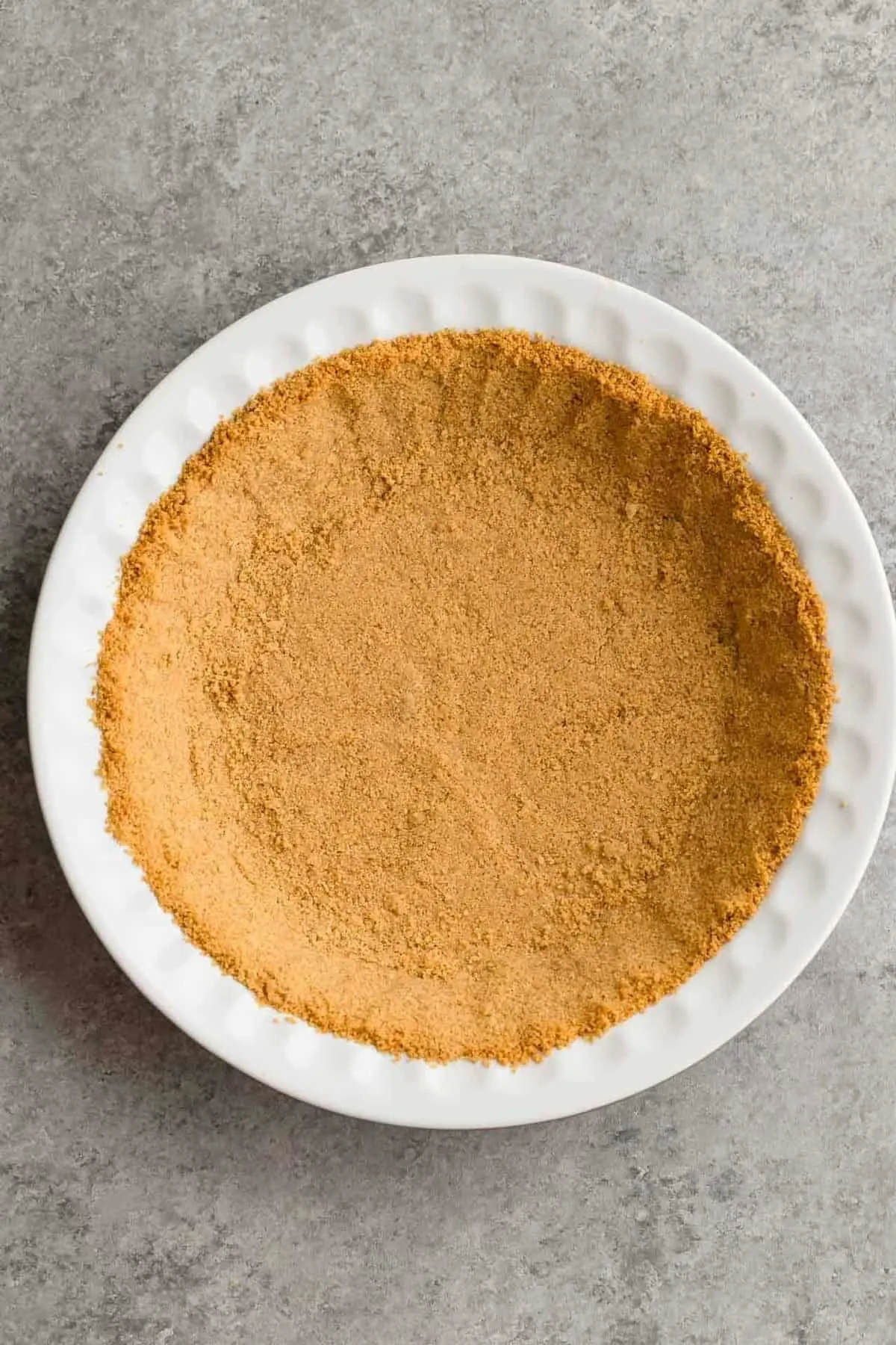 Graham cracker crumbs pressed into a white pie dish.