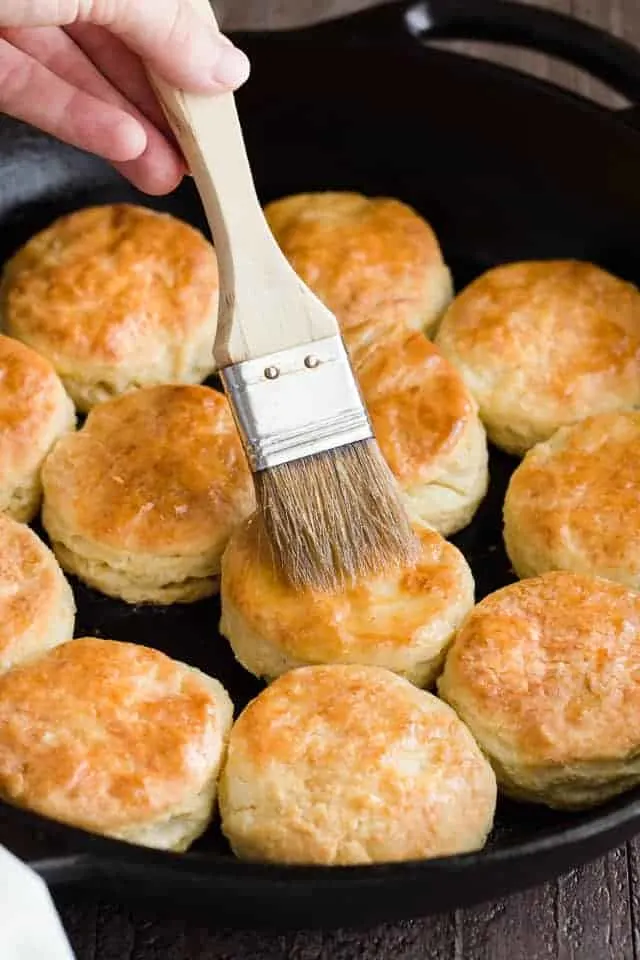 Brushing butter over over honey cream cheese biscuits with a pastry brush.