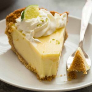 Close up view of lime pie in a white plate with a fork taking out a bite.