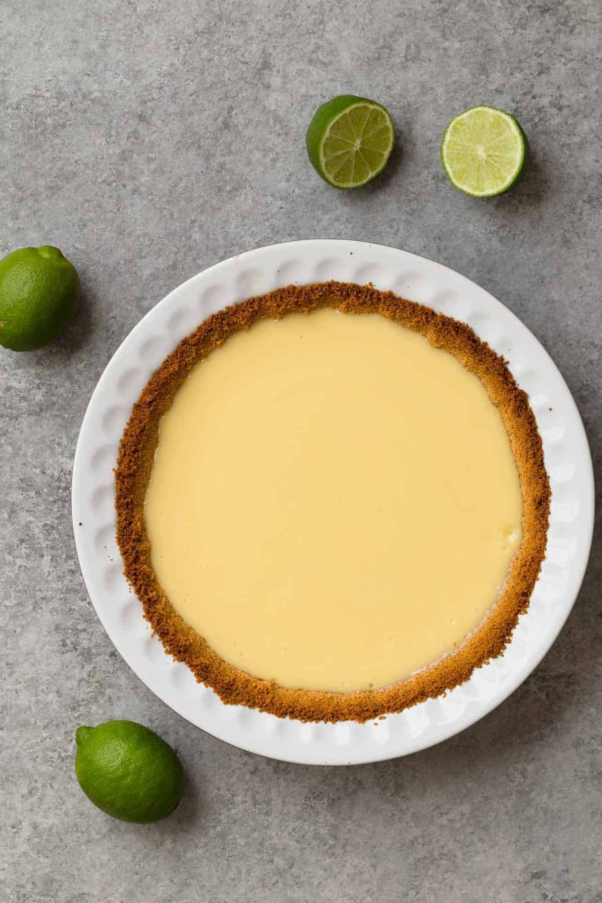 Lime pie with graham cracker crust baked in a white pie dish.