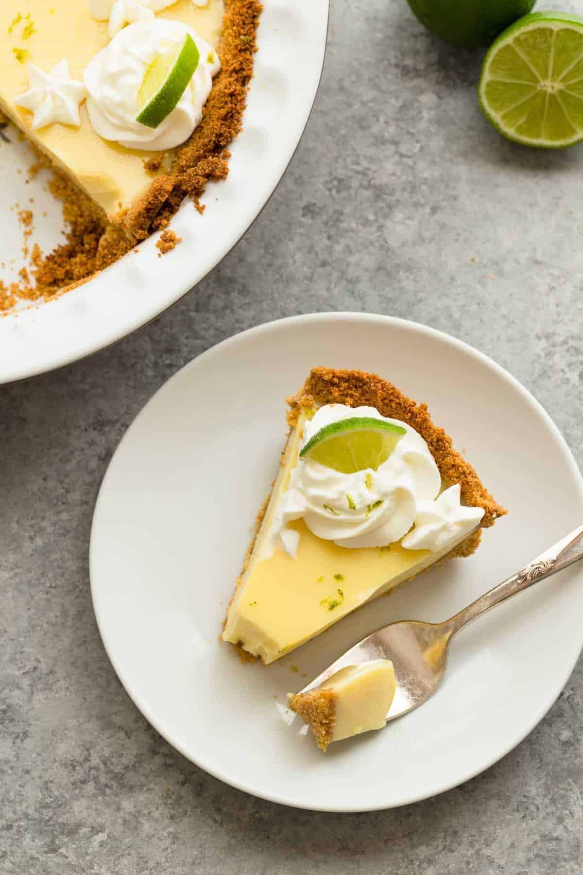 A slice of lime pie on a white plate with a fork taking out a bite.