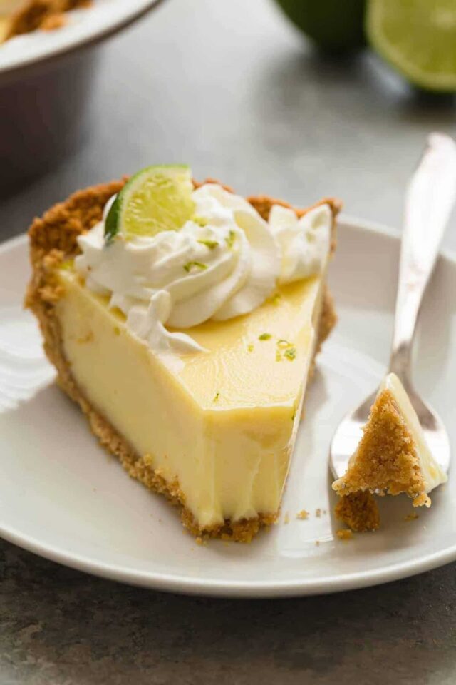 Close up view of lime pie in a white plate with a fork taking out a bite.