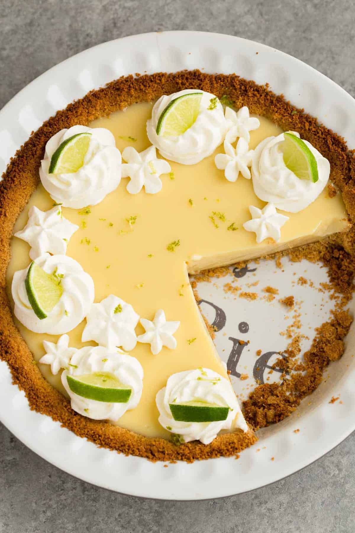 Lime pie in a white pie dish with a slice missing.